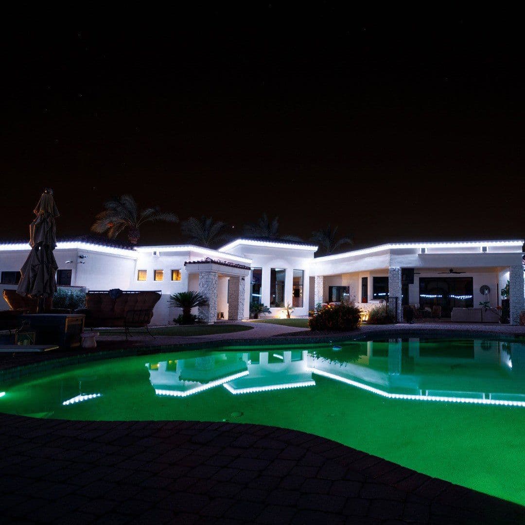 Luxurious modern home at night with illuminated pool and palm trees in serene setting.