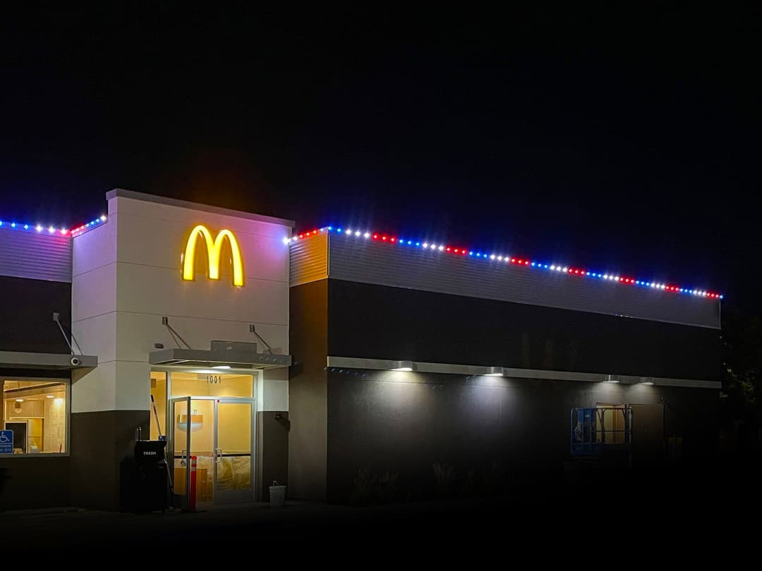 McDonald's storefront at night, featuring illuminated signage and festive exterior lighting.