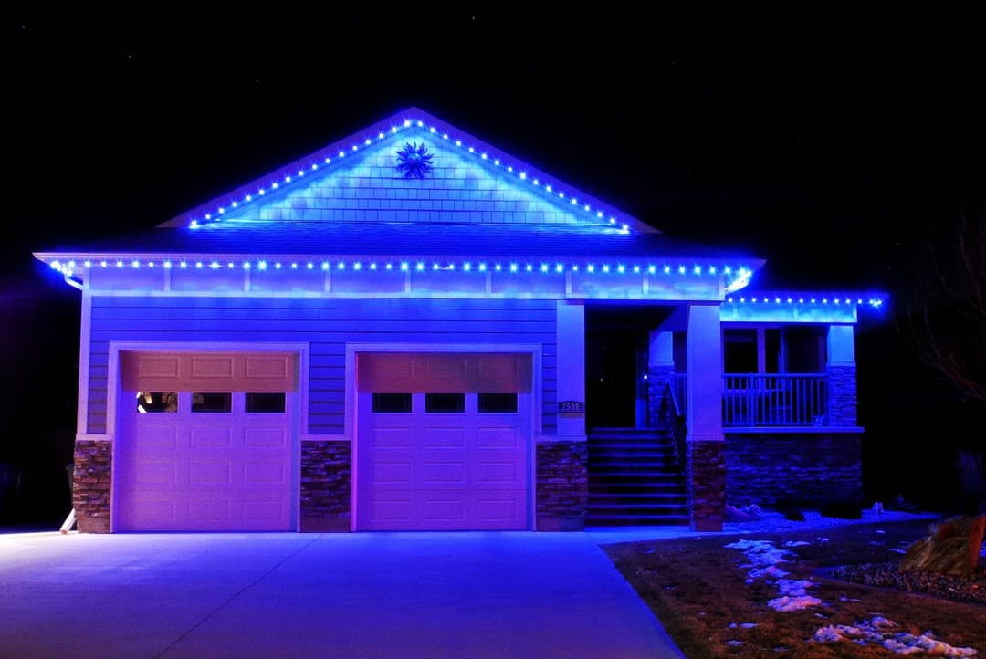 Modern home illuminated with blue LED lights at night, showcasing festive holiday decoration.