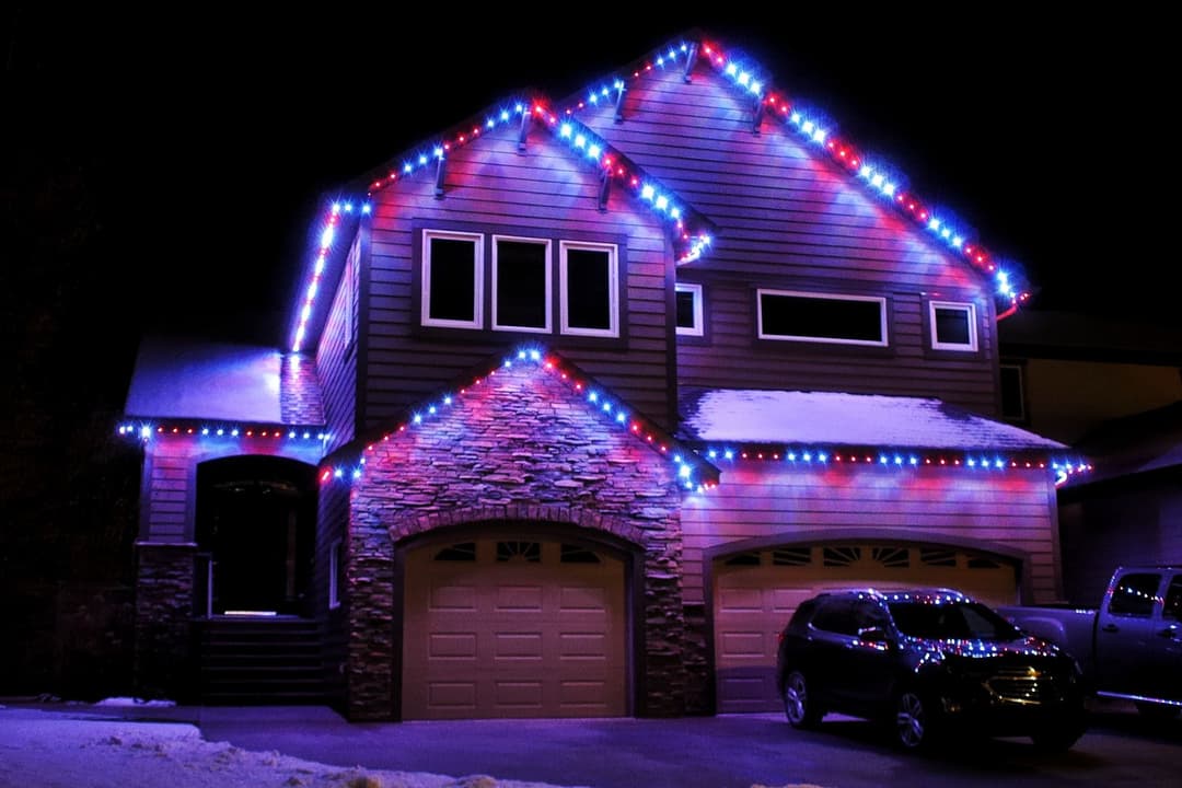 Festively decorated home with colorful Christmas lights on a snowy night.