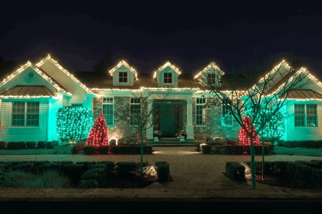Festively lit home with green and red Christmas lights, showcasing holiday spirit at night.