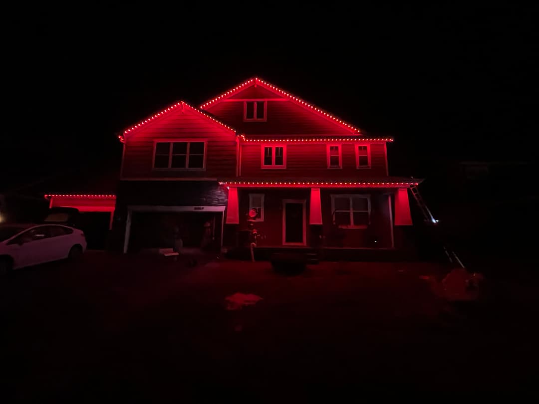 House illuminated with red lights at night, creating a festive holiday atmosphere.